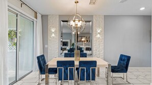 A dining area with a rectangular table, six chairs, and a central chandelier. - Golf  & splash vacation homes, close to Disney (Kissimmee)