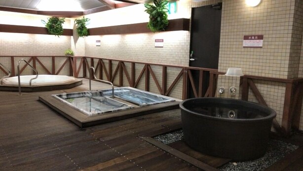 Een wellnessruimte met een jacuzzi, een rechthoekig bad en een groot zwart bad.