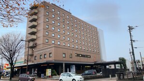 Een hotel met meerdere verdiepingen, een bakstenen gevel, diverse balkons en een gelijkvloerse ingang met borden.