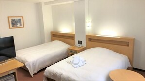 Een hotelkamer met twee bedden, een bureau, een stoel en een klein rond tafeltje.