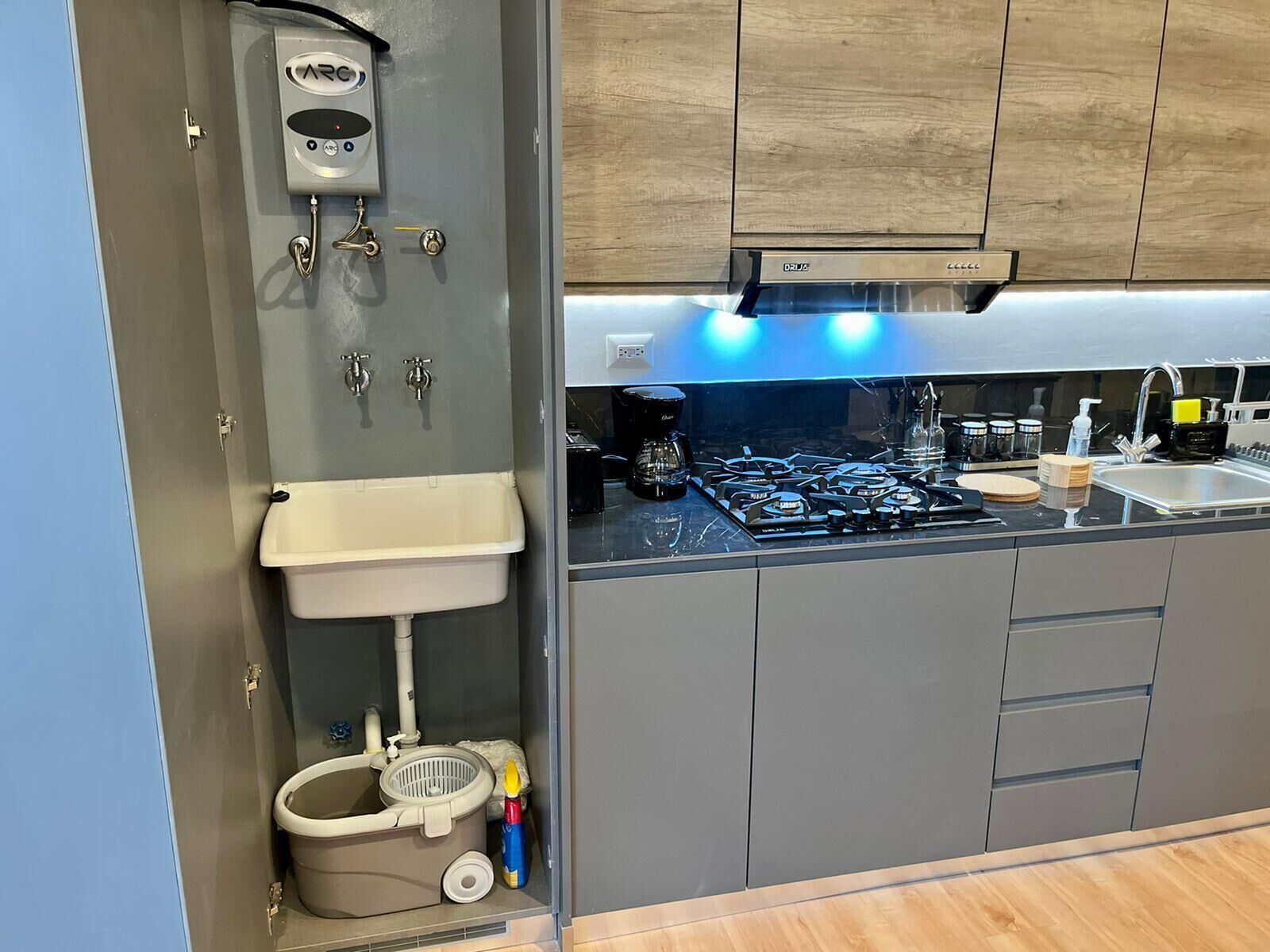 A compact kitchen with a built-in sink, a stove, and a compact toilet.