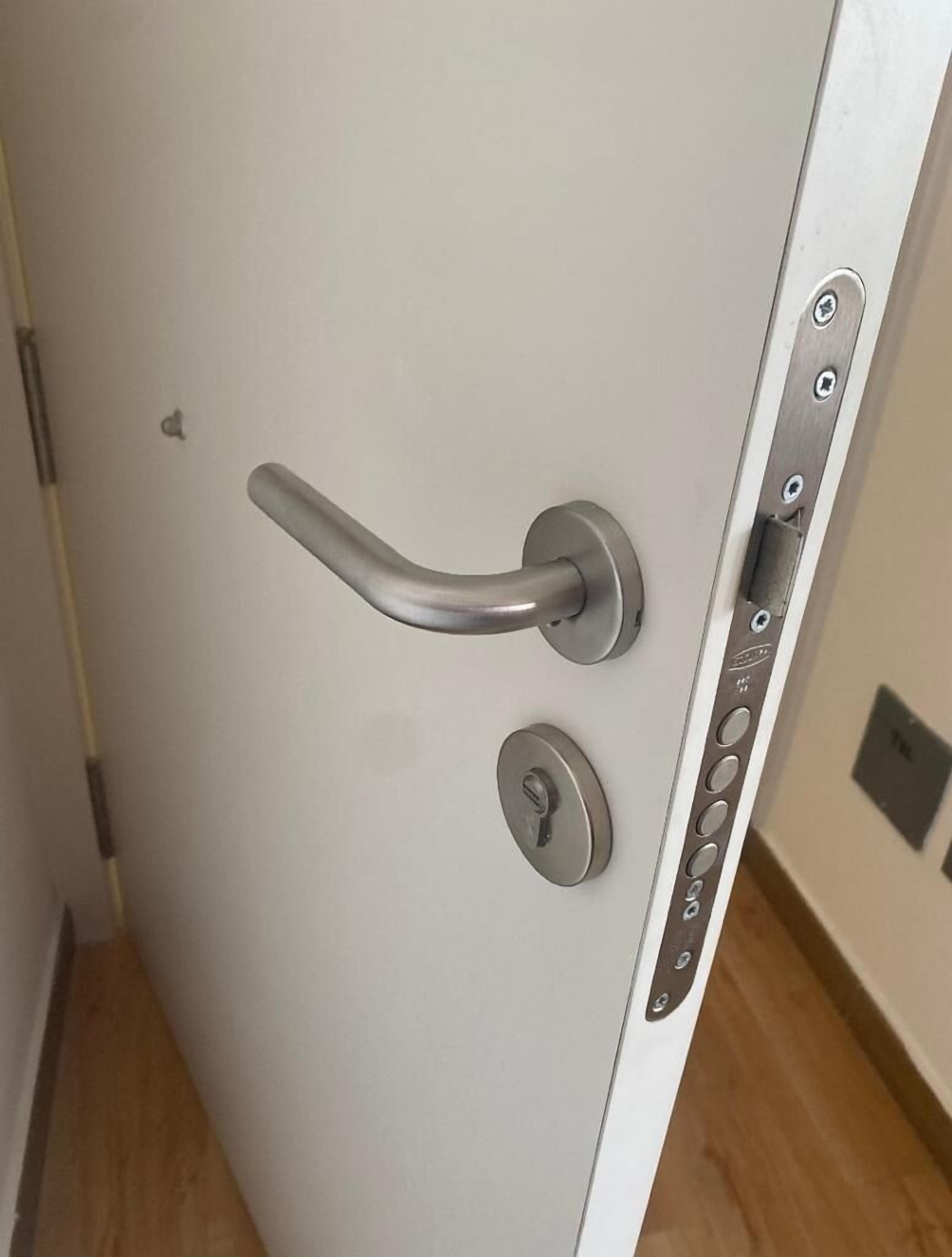 Una puerta moderna con manija metálica, un ojo de cerradura y un panel de control con botones.