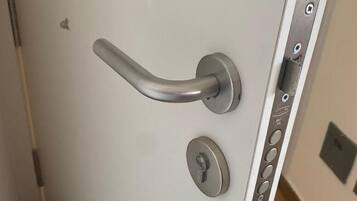 Una puerta moderna con manija metálica, un ojo de cerradura y un panel de control con botones.