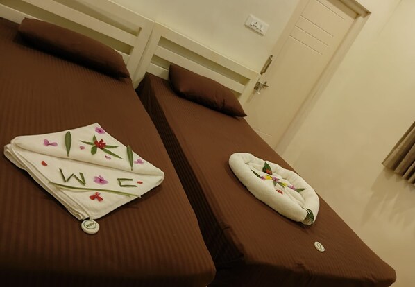 Two single beds with brown bedding and a white pillow with floral decorations. - Bamboo Nest (Pollachi)