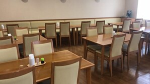 Un restaurante con mesas y sillas de madera, un techo alto y una barra larga.