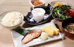 Uma refeição com arroz, peixe e legumes sobre uma mesa de madeira.