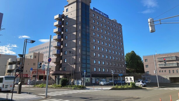 A multi-story hotel with a prominent tower, balconies, and a clear sky. - Hotel Alpha-One Sabae (Sabae)