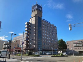 Um hotel com vários andares, uma torre imponente, varandas e céu claro.