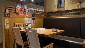 A restaurant interior with wooden tables and chairs, a booth seating area, and various menu posters on the walls. - Hotel Alpha-One Sabae (Sabae)