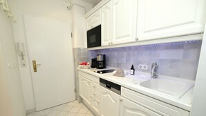 A modern kitchen with white cabinetry, a built-in microwave, a coffee maker, and a sink.
