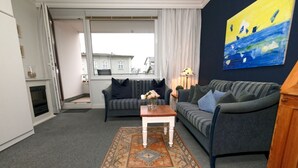 A living room with a sofa, a coffee table, a rug, and a painting on the wall.