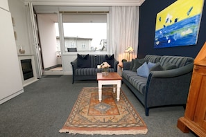 A living room with a sofa, a coffee table, a rug, and a painting on the wall.