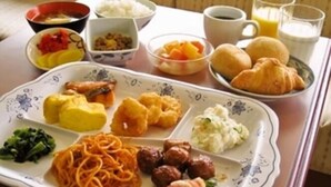 Un plato de desayuno con espagueti, albóndigas, cruasanes y fruta.