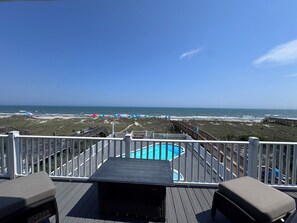 A deck with a pool, overlooking a beach with umbrellas and a clear sky. - Alternative Wave I Gorgeous Oceanfront House with Private Pool and Great Views! (Ocean Isle Beach)
