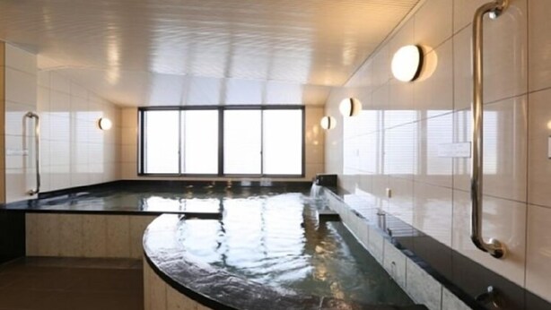 A modern spa area with a curved black marble counter, a glass-enclosed hot tub, and a large window providing natural light. - Hotel Alpha-One Tsuruga-Bypass (Tsuruga)