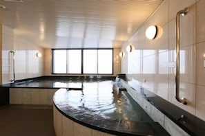 A modern spa area with a curved black marble counter, a glass-enclosed hot tub, and a large window providing natural light. - Hotel Alpha-One Tsuruga-Bypass (Tsuruga)