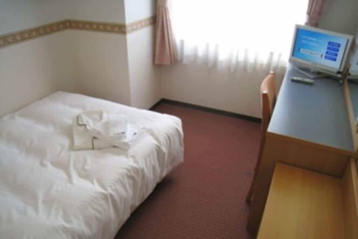 Habitación de hotel con una cama, un escritorio y una computadora.