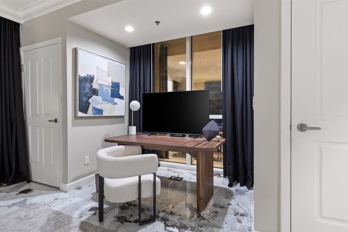 Una sala de estar moderna con un televisor de pantalla plana, una mesa de centro de madera y un sillón blanco.
