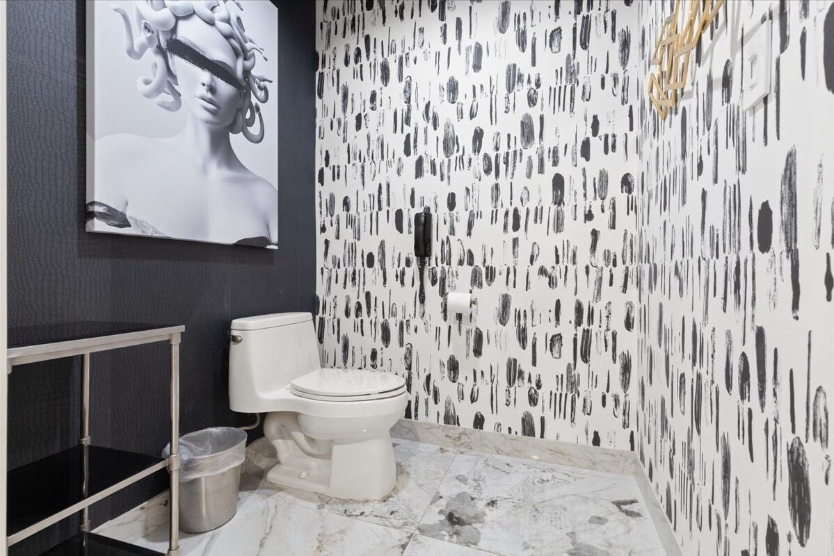Un bagno con un water, una mensola metallica e un cestino.