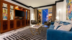 A modern living room with a large flat-screen TV, a blue sofa, and a checkered rug.