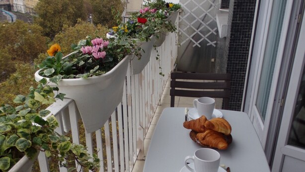 A balcony with a table set for two, a bench, and potted plants. - Sweet Home Panoramic Sacré Coeur  (Paris)
