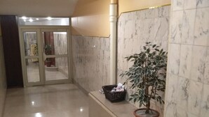 A hallway with a marble floor, a potted plant, a wicker basket, and a door leading to another room. - Sweet Home Panoramic Sacré Coeur  (Paris)