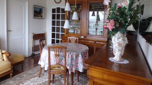 A dining area with a wooden table, chairs, a vase with flowers, and a bookshelf with books. - Sweet Home Panoramic Sacré Coeur  (Paris)