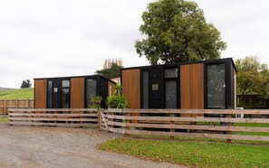 Un bâtiment moderne avec une clôture en bois à l’avant, entouré de verdure.
