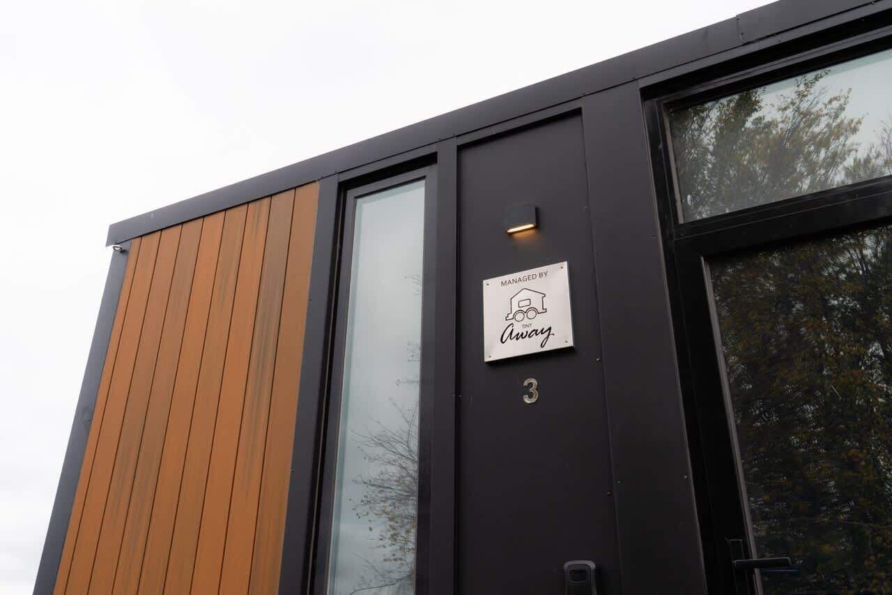 A modern building with a wooden panel facade, a large window, and a sign indicating it is managed by Away.