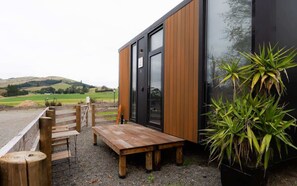 Un bâtiment moderne avec des panneaux extérieurs en bois, une grande porte en verre et un banc en bois à l’extérieur.