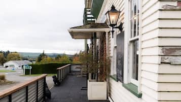 A building with a covered outdoor area, a street sign, and a view of the countryside.