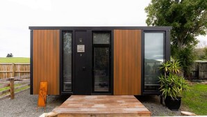 A modern, single-story building with a wooden exterior and large glass windows. - Weka Pass Cottages 3 by Tiny Away (Waikari)