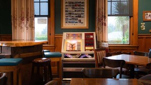 A cozy restaurant with wooden furniture, a jukebox, and framed photos on the wall. - Weka Pass Cottages 3 by Tiny Away (Waikari)