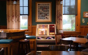 Een gezellig restaurant met houten meubels, een jukebox en ingelijste foto’s aan de muur.