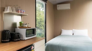A hotel room with a bed, a microwave, a coffee maker, and a shelf with glasses and snacks. - Weka Pass Cottages 3 by Tiny Away (Waikari)