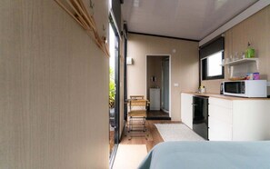 Een compacte, moderne keuken met een magnetron, een kleine koelkast en een houten aanrecht.