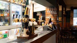 Un espace bar équipé d’une machine à café, d’une caisse enregistreuse et d’un réfrigérateur rempli de boissons.