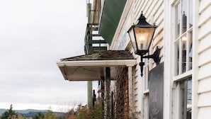 Un bâtiment doté d’un espace extérieur couvert avec des sièges, d’une lanterne noire et d’une enseigne indiquant qu’un bar est ouvert.