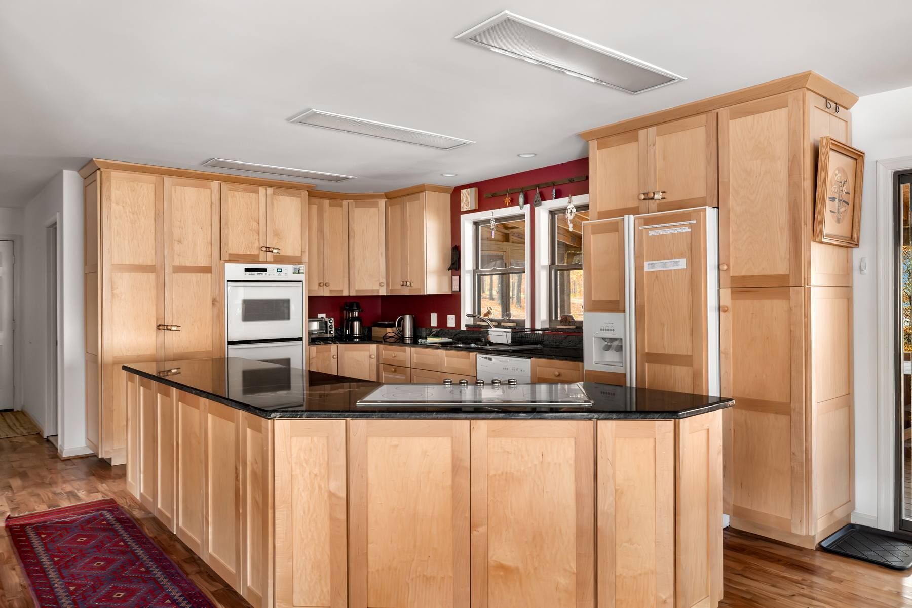 A modern kitchen with wooden cabinets, a central island, and built-in appliances.