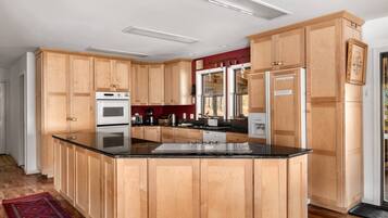 A modern kitchen with wooden cabinets, a central island, and built-in appliances.