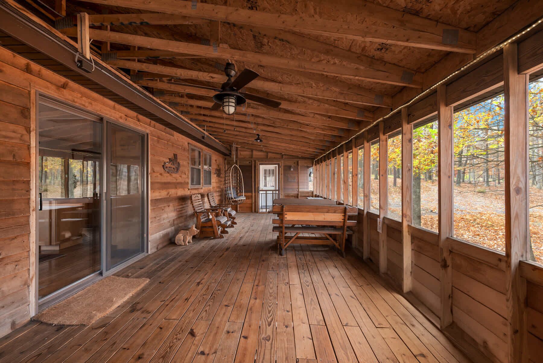 Eine Holzhütte mit Veranda, großen Fenstern und einem Deckenventilator.