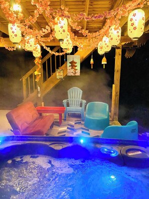 A hot tub area with seating, a staircase, and decorative lanterns.