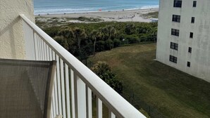 Uma varanda com vista para a praia e um prédio.