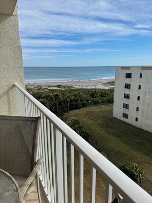 A balcony with a view of a beach and a building. - Ocean View Condo • Pool • Beachy Getaway (Cocoa Beach)