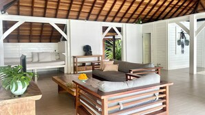 A spacious living area with a high wooden ceiling, a sofa set, a wooden coffee table, and a potted plant. - Charming 3-bedroom family villa in Berawa (Bali)