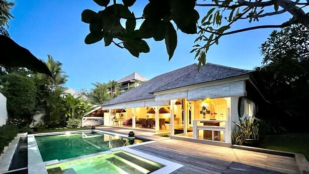 A modern house with a swimming pool, wooden deck, and a covered outdoor area with seating. - Charming 3-bedroom family villa in Berawa (Bali)