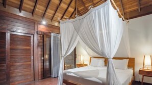A bedroom with a canopy bed, wooden flooring, and a wooden ceiling. - Charming 3-bedroom family villa in Berawa (Bali)