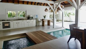 A modern kitchen with white cabinets, a wooden countertop, and a large window. - Charming 3-bedroom family villa in Berawa (Bali)