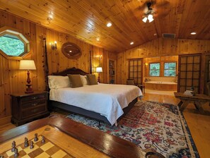 Een slaapkamer in een houten chalet met een bed, een bureau, een schaakbord en een bad.