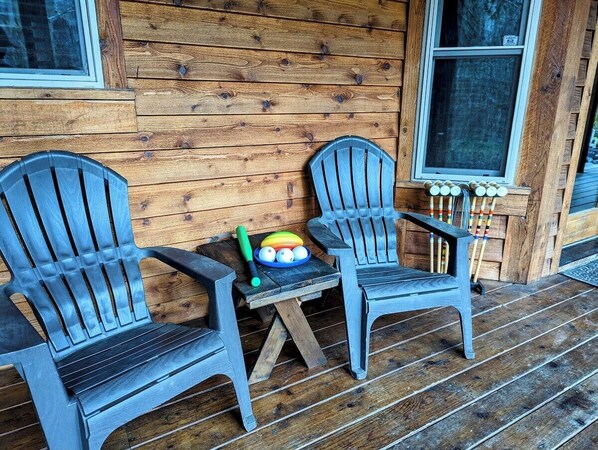 Two Adirondack chairs on a wooden porch with a small table between them. - Summer Lodge Life! 5bd+4bath+HotTub+Sauna+EV (Ashford)